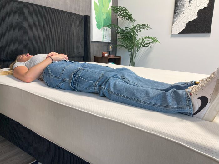 A woman lays on her back on the Boring AF mattress