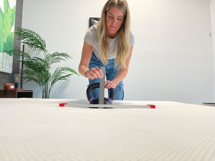 A woman measures sinkage with a kettlebell
