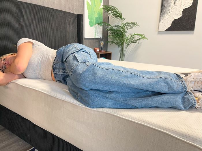 A woman sleeps on her side on the Boring AF mattress