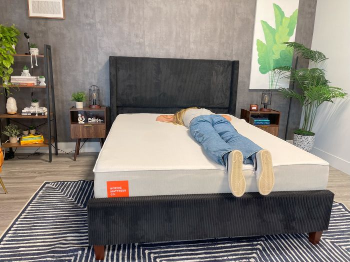 A woman sleeps on her stomach on the Boring AF mattress