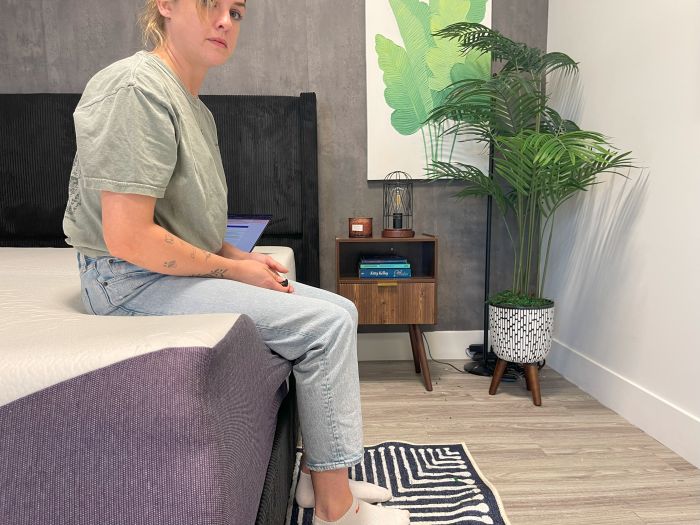 A woman sits on the edge of the Polysleep Luna mattress