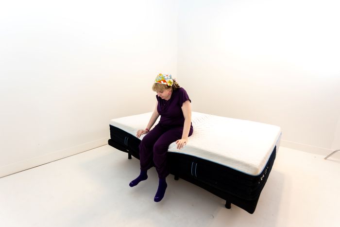 A woman sits on the edge of the Nectar Classic Hybrid mattress.