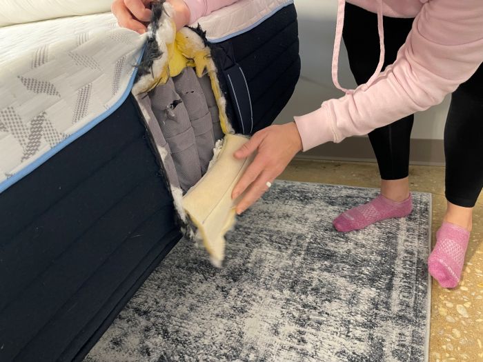 A woman showing the layers of the Nectar Classic Hybrid mattress.