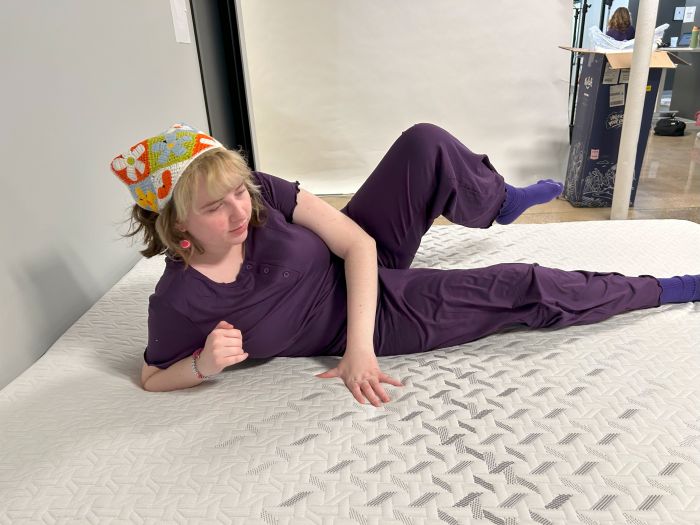 A woman shows switching positions on the Nectar Classic Hybrid mattress.