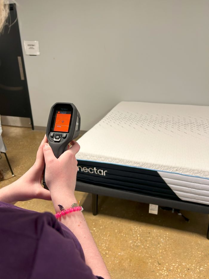 A woman uses a temperature gun on the Nectar Classic Hybrid mattress.