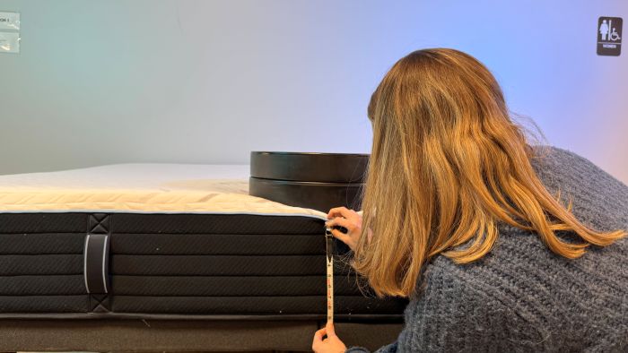 A woman places weights on the Nectar Classic Hybrid mattress to measure sinkage.