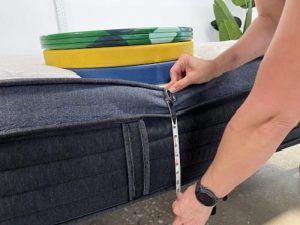 Measuring weight plates on the edge of a Helix Midnight Luxe Mattress