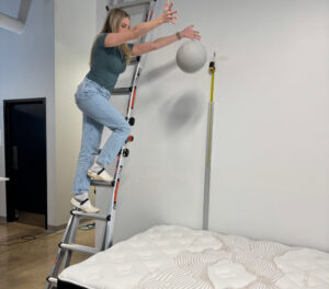 Our tester drops a ball from a ladder during a bounce test on the Nolah Evolution Mattress.