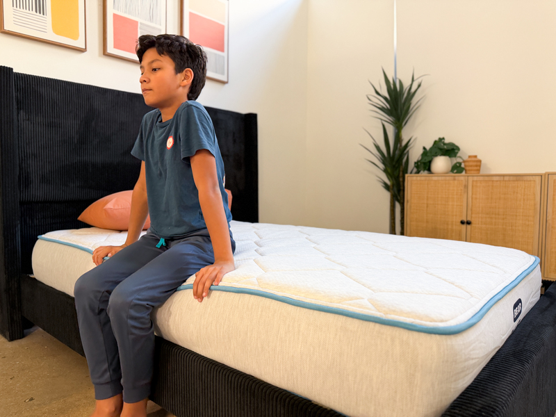 A young tester sits on the edge of the Bear Cub mattress.