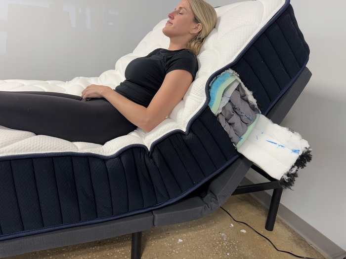 Woman resting on the DreamCloud Classic Hybrid with the head of the mattress elevated by an adjustable base