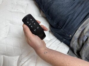 Holding the remote control for a Brooklyn Bedding Ascension Luxe Adjustable Base