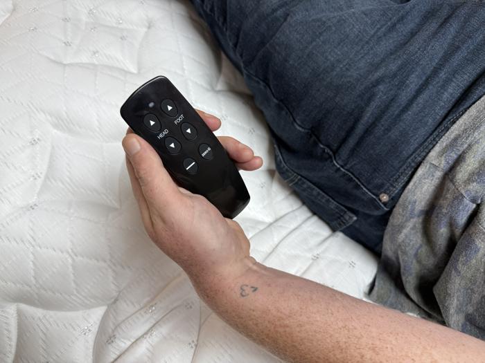 Holding the remote control for a Brooklyn Bedding Ascension Luxe Adjustable Base
