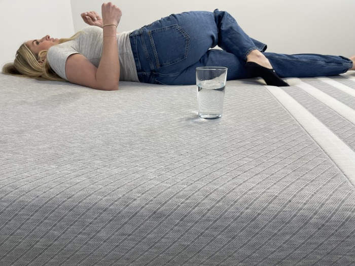 Testing motion isolation on the Leesa Original mattress by moving on the bed near a glass of water