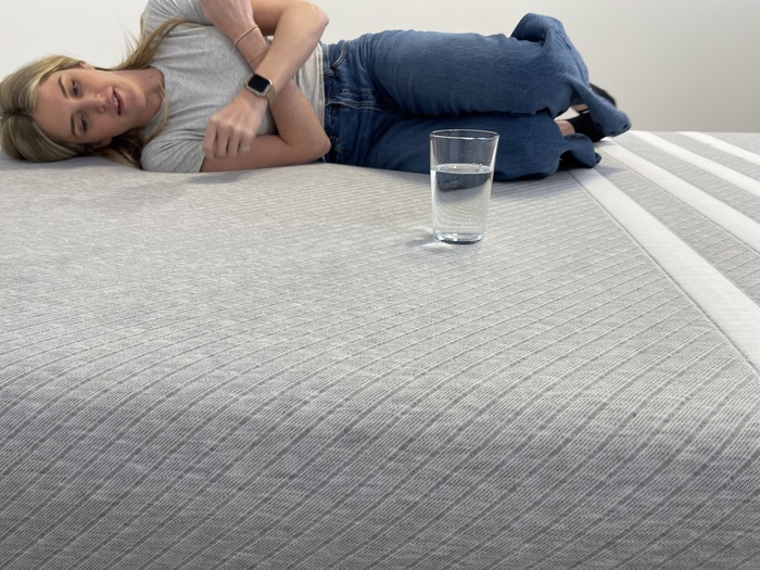 Testing motion isolation on the Leesa Original mattress by moving on the bed near a glass of water