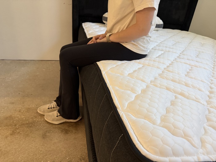 Testing edge support by sitting on the perimeter of the Titan Plus Core mattress