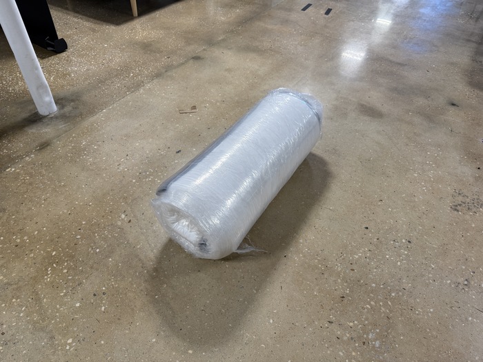 The Titan Plus Core mattress rolled up in plastic after being unboxed