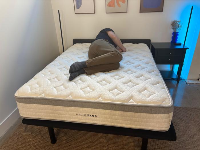 Our tester side-sleeping on the Helix Plus Mattress